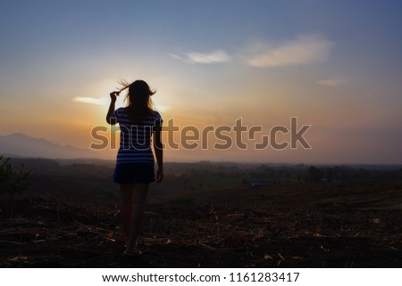 Woman is walking in dry grass field and relaxing on looking at sunset on the mountain. from Mae Sot, Tak,Thailand in the sunset.