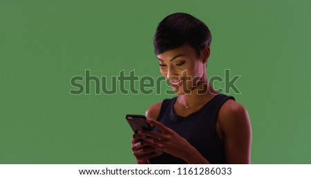 Portrait of African American female texting on smartphone on green screen
