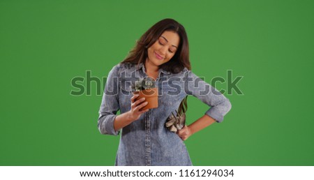 Hispanic woman gardener holding small potted plant posing on green screen