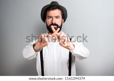 Hipster man with beard making NO gesture on grey background