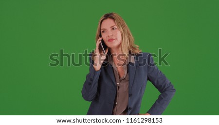 Middle aged adult Caucasian businesswoman chatting on smartphone on green screen