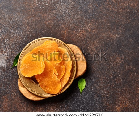 Dried mango slices. Top view of candied fruits on brown background.
