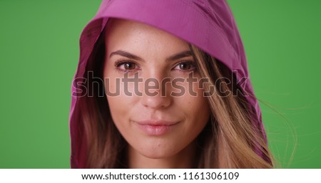 Attractive white girl looking at the camera in a pink rain coat on green screen