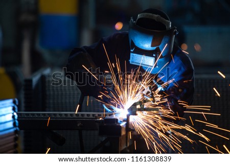 Workers wearing industrial uniforms and Welded Iron Mask at Steel welding plants, industrial safety first concept. Royalty-Free Stock Photo #1161308839