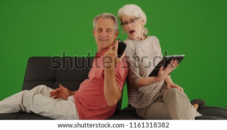Mature husband showing wife something on phone on green screen