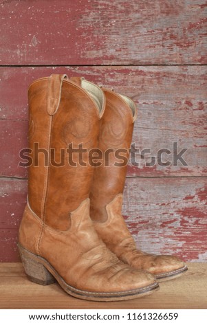 cowboy boots with a background of red barn board