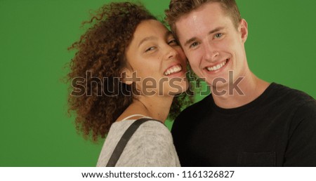 Millennial couple smiling at camera standing close together on green screen
