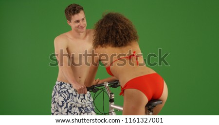 Handsome white male flirting with cute woman in bikini on bike on green screen