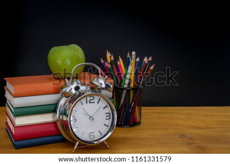back to school concept. stack of books and pencils over wooden desk in front of blackboard