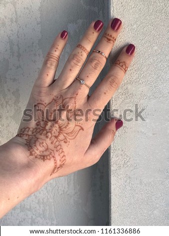 Woman's hand with traditional menhdi henna ornament on concrete background.