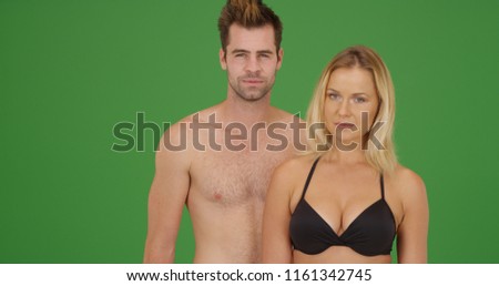 White millennial couple in swimsuits looking at camera on green screen