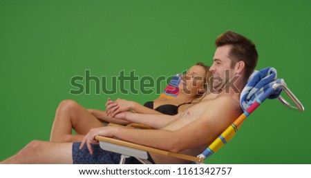 Young white couple sunbathing and holding hands on green screen