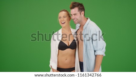 Happy Caucasian millennial couple in swimwear standing on green screen