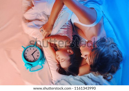 Low key night light picture of mother and daughter in bed