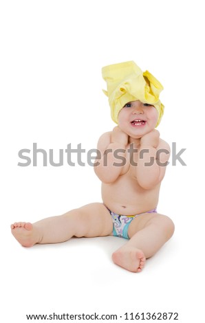 
Cute one year baby getting dressed. Funny little girl put shorts on her head. Isolated on white background