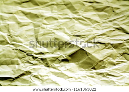 Crumpled sheet of paper with blur effect in yellow tone. Abstract background and texture for design.