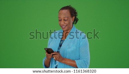 Black elderly woman uses smartphone to text on green screen