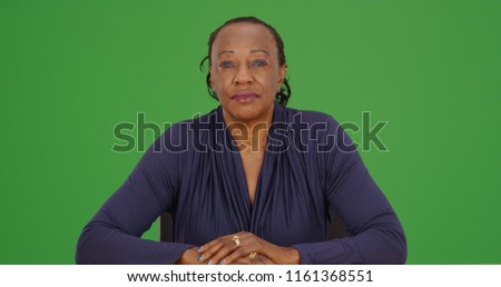 African American woman sitting and looking at camera on green screen