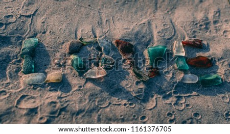 Love written with sea glass in the sand