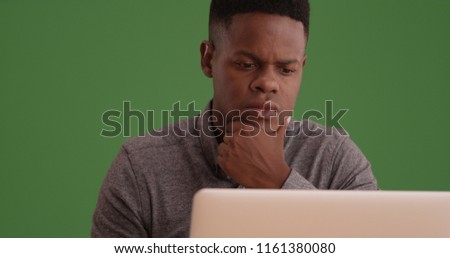 Young black man working on a laptop on green screen