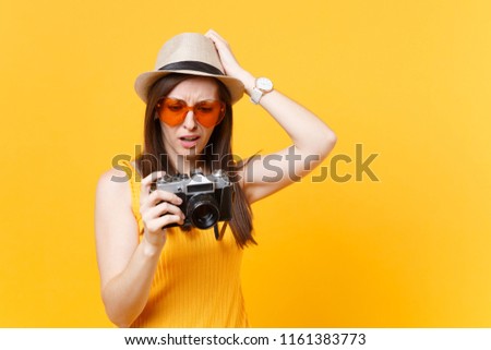 Tourist woman in summer casual clothes, hat take picture on retro vintage photo camera isolated on yellow background. Girl traveling abroad to travel on weekends getaway. Air flight journey concept