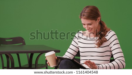 Beautiful girl watching video on tablet at cafe on green screen