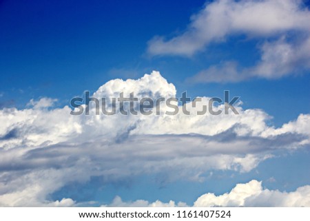 White clouds of various shapes against the blue sky and sun. The game of light and shadows in various variations of the sun's lighting clouds.