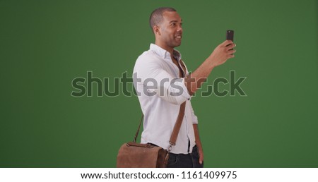 A young black man records video on his mobile phone on green screen