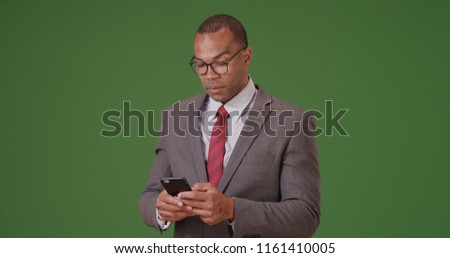 A black man uses his phone for business on green screen
