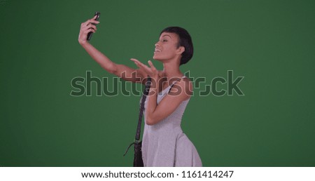 Woman blowing kiss and taking a selfie picture with smartphone on green screen