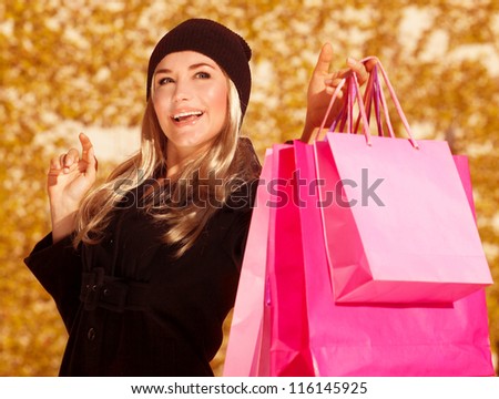 Picture of shopper girl holding presents bags in hand, beautiful customer enjoy autumnal season sales, closeup portrait of cheerful woman with shopping bag isolated on fall foliage background