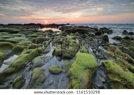 Sunset view with rocks covered with green moss at Kudat Sabah Malaysia. A famous place and most visited for photographers to take pictures.

