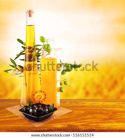 Picture of olive oil still life on wooden table over sunset, glass jar with oil and fresh olives vegetables on yellow gardening background, italian salad dressing, healthy nutrition concept