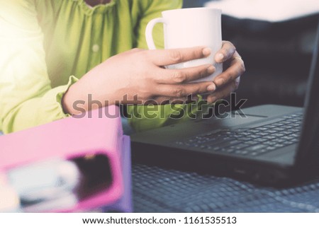 Hands of businesswoman in casual dress holding coffee cup while planning for online ordering with laptop via the internet. Business And Financial Concept.