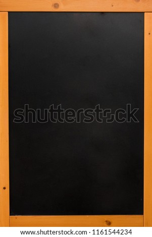 wood frame blackboard  with brown colour standing on the street with people walking pass and blackboard frame empty word.Have space to put an advertise or menu inside