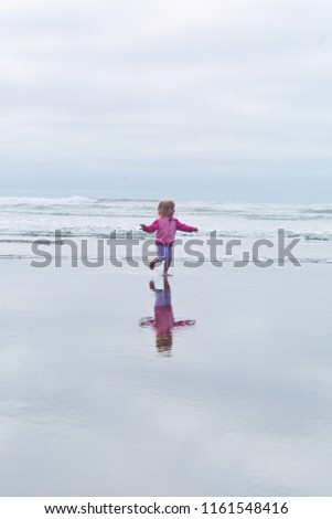 Small, Cute, Toddler Girl, Blonde hair and blue eyes, in pink hoodie, playing in the water, running, Pacific Ocean, Oregon coast, family vacation time, reflection in the water