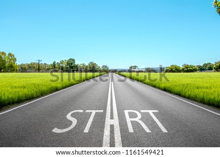 Driving on an empty asphalt road through the idyllic fields at . Concept vision for a new beginning with a sign start 