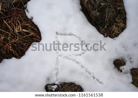 Close up handwriting alphabet 'R' on pile of snow
