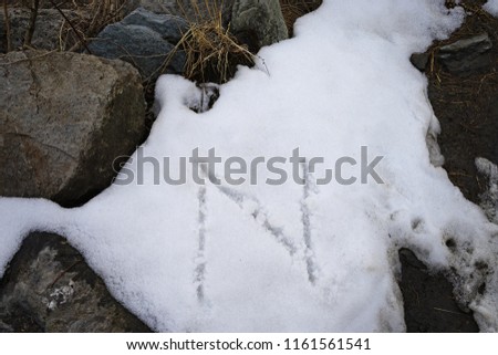 Handwriting alphabet 'N' on pile of snow
