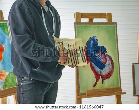 Handsome Young Asian man or water color artist Teaching how to use paintbrush in Classroom,fish concept