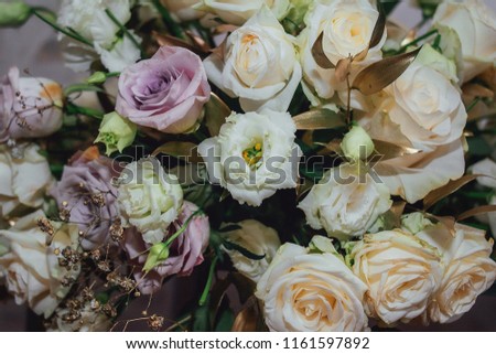 Closeup photo of wedding bouquet with white and violet pastel roses. Creme toning. Natural decoration for home.