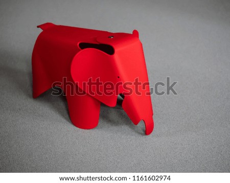 Red elephant toy chair in a grey office.