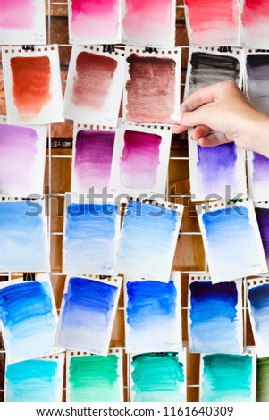 watercolors swatch assortment background. ink dyes colors mix on paper. art painting and drawing. inspiration and creativity. artist skills practice. free space concept. woman hand choosing.