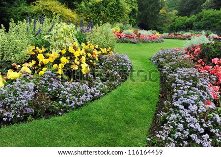 Colourful Flowerbeds and Winding Grass Pathway in an Attractive English Formal Garden Royalty-Free Stock Photo #116164459