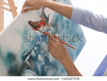 Male artist painting on canvas on white background