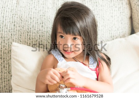 Asian cute little girl is smiling and playing doctor with stethoscope. Kid and health care concept.