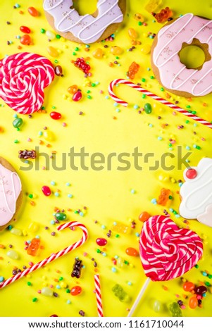 Sweets creative lay out, dessert concept with lollipops, jellies, candy, cookies donuts and cupcakes, bright yellow background top view copy space