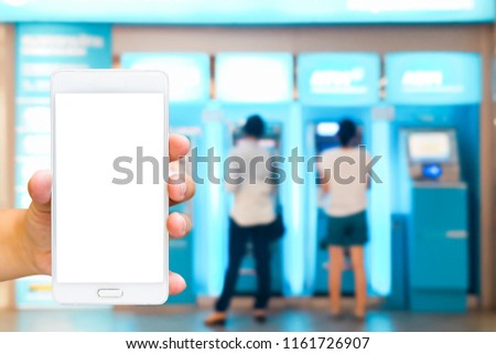 Girl use mobile phone, blur image of people stand at ATM machine as background.