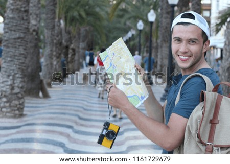 Joyful tourist holding map and camera during a vacation