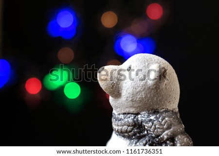 toy polar bear on a black background with lights of Christmas garlands. Close-up